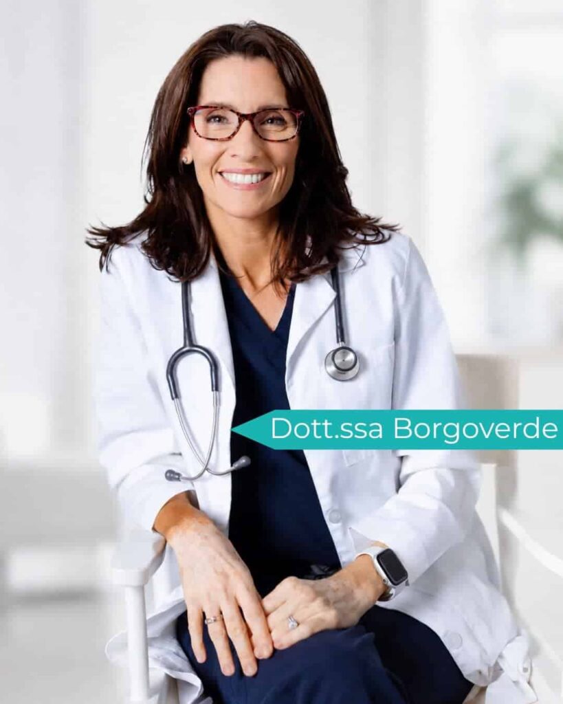 Medico donna sorridente con camice e stetoscopio in studio medico.